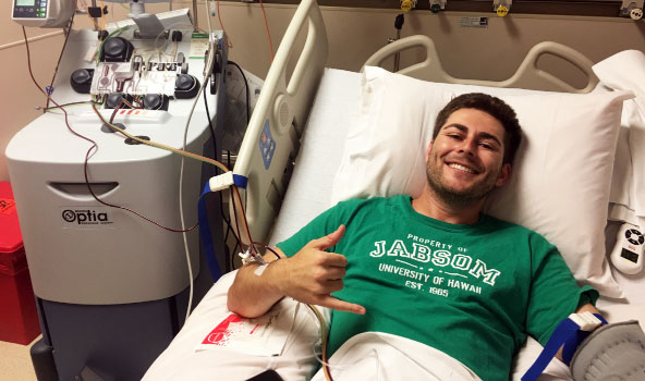 Young male donor on hospital bed smiling showing Hawaiian shaka hand sign